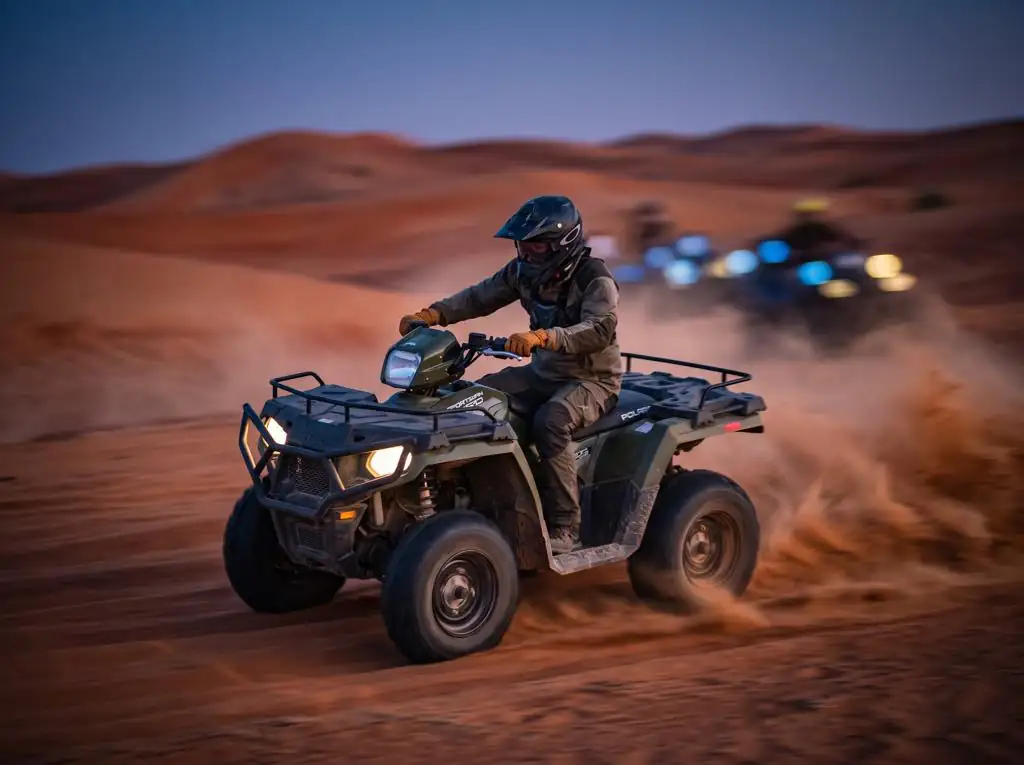 Polaris Sportsman 570 quad bike with headlights on in red Dubai dunes